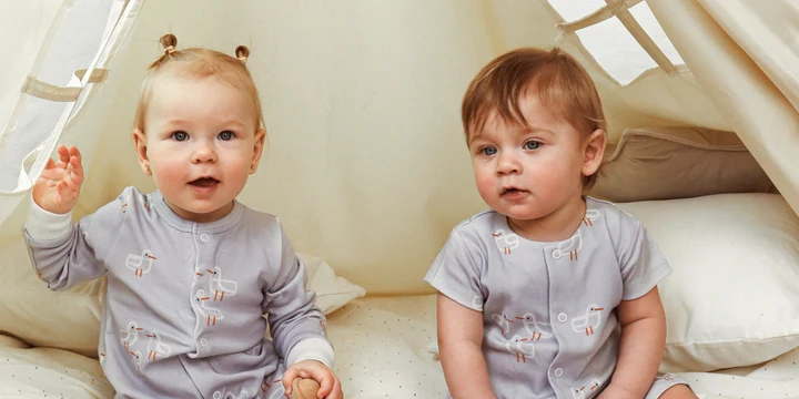 Two children sitting in a light tent, wearing LilliOli clothing with seagull prints.