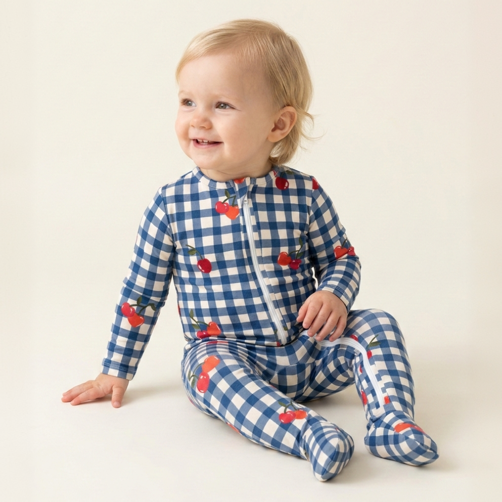 Baby zittend in gingham-pyjama met kersen, lachend
