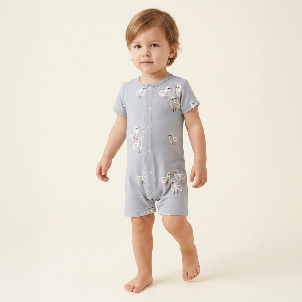 Baby in een zeemeeuwen-romper, staand in een warme studio